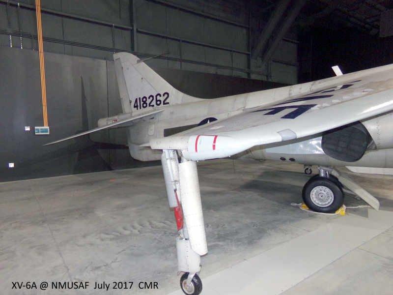 A light‑colored XV‑6A aircraft displayed indoors at the National Museum of the U.S. Air Force, shown from a left‑side angle with the landing gear, wheel chocks, and tail number “418262” visible. The aircraft sits on a concrete floor inside a dark‑walled hangar gallery.