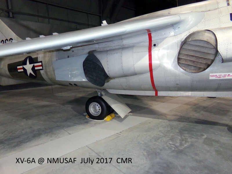 Close‑up left‑side view of an XV‑6A aircraft on display at the National Museum of the U.S. Air Force, showing the rear main landing gear with a wheel chock, the U.S. Air Force roundel, intake and exhaust ports, and detailed panel lines on the metallic fuselage. 